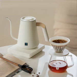 Hvit elektrisk vannkoker med smal tut og tre-detalj for presis helling ved kaffebrygging, alt om kaffe.