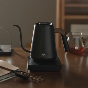 Svart elektrisk vannkoker med smal tut og trehåndtak for barista- og bryggtilbehør fra Timemore, alt om kaffe.