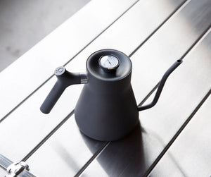 Matt svart vannkoker med smal svanehals og innebygd termometer, bryggetilbehør, alt om kaffe.