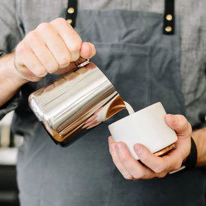 Barista heller melk fra polert kanne i rustfritt stål, del av Espresso-tilbehør og melkekanne, alt om kaffe.