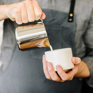 Barista heller melk fra polert kanne i rustfritt stål, del av Espresso-tilbehør og melkekanne, alt om kaffe.