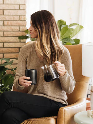 Kvinne i beige genser med barista espresso-serveringskanne i glass, moderne design, siste nytt, alt om kaffe.